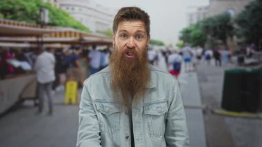 Sessiz kalmak için parmakları dudaklarına kadar parmakları olan bir adam şehir sokaklarında hediyelik eşya tezgahları; sessiz bir gizlilik.