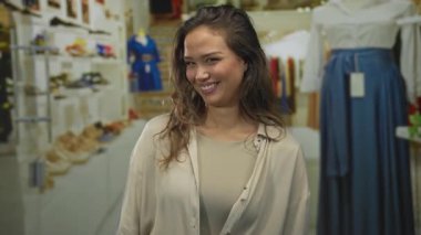 Genç İspanyol kadın gülümser ve ayakkabı dolu giyim mağazasında ellerini açar; hoş geldiniz..