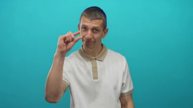 Beyaz gömlekli adam, küçük boyutta veya minimum konsept ifade eden izole edilmiş mavi duvara karşı küçük bir jest yapıyor..