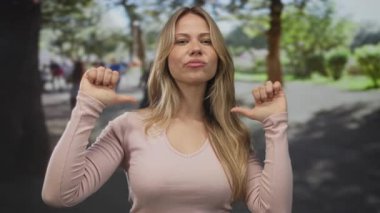 Parlak güneş ışığı ve ağaçların altındaki yeşil parkta kadın göğsünde duruyor ve başparmak uçlarında duruyor; güven gururu.