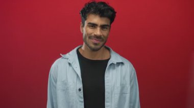 Stüdyoda göz teması kurarken gülümseyen ve kamerayı işaret eden adam; güven ilhamı bağlantısı.