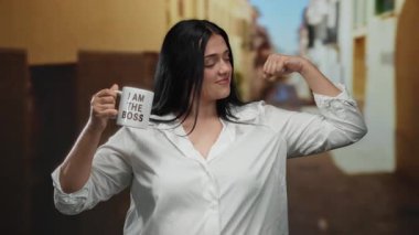 Beyaz gömlekli, kendine güvenen bir kadın elinde fincanla poz veriyor. Ben patronun şehir sokaklarında esneme hareketiyim, güç ve güç taşıyorum..