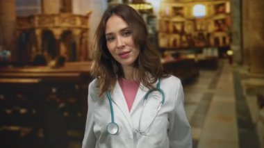 Steteskoplu İspanyol kadın doktor kilisede jest yapıyor. Tıp mesleğini dini bir ortamda beklenmedik davranışlarla harmanlıyor..