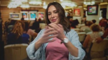 Canlı resimler ve izleyicilerle sanat galerisi ortamında gülümseyen bir kadın, rahat bir sanat ortamında mutluluk ve kültürel bağlantıyı somutlaştırıyor..