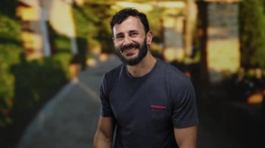 Sokakta sakallı İspanyol bir adam sessizce el sallıyor.