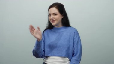 Mavi süveterli bir kadın, gri arka planda öpüşürken mutluluk ve sıcaklık saçar. Nazik gülümsemesi ve anlamlı gözleriyle samimi bir sevgi gösterisi sunar..