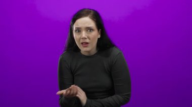 Şoka girmiş bir kadın, elleri yüzünde canlı mor arka planda dramatik bir stüdyo ortamında şaşkınlık ve duyguyu canlandırıyor..