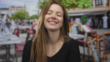 Restoran terasında dişlerini gösteren bir kadın. Gün ışığında pencere inşa etmenin yanında boş masalar. Huzur..