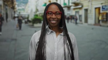 Şehirdeki sokakta el sıkışmak için elini uzatan kadın, şehir arka planında bulanık, açık havada dostça bir etkileşime işaret ediyor..