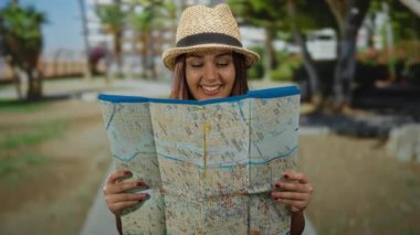 Açık havada gülümseyen ve elinde haritayla gezen İspanyol bir turist..