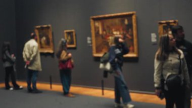 Müzedeki bulanık insanlar sanata hayran, arka planda çözünmüş resimler olan kapalı mekan ortamları, barışçıl bir galeri atmosferi yakaladılar..