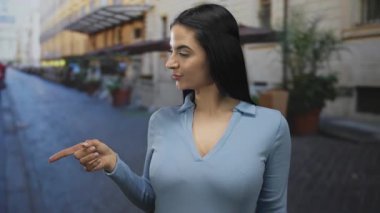 Mavi gömlekli genç bir kadın, şehir arka planında gülümserken Latin kültürünün etkisiyle şehir yaşamını gözler önüne seriyor..