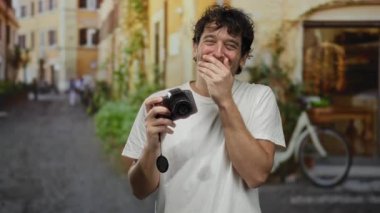 Çekici bir Akdeniz kasabasında gülümseyen ve elinde kamera tutan İspanyol bir adam, eski bir sokakta canlı bir fotoğraf çekimi yapıyor..