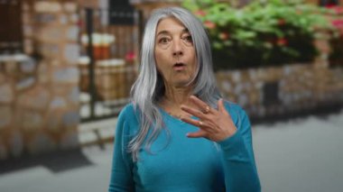 Çiçekler ve taş duvarlarla büyüleyici bir caddede dikilen bir kadın dış mekan kentsel ortamlarında son sınıf anılarını sergiliyor..