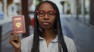 Rus pasaportlu bir kadın şehir merkezinde gözlüklü, çizgili tişörtlü, gezici ve kimlik temalı bir kadın..