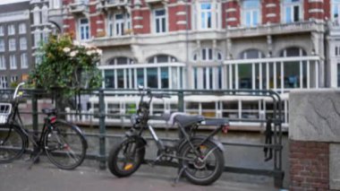Amsterdam Kanalı yakınlarındaki bulanık bisikletler, dağılmış tarihi bina, tipik Hollanda şehir manzarası cazibesi ve kentsel dekor sergiliyor.