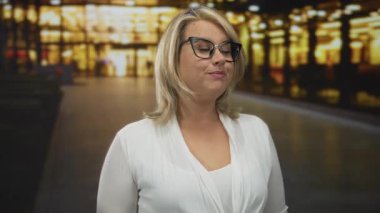 Kadın telefon şeklindeki elini kulağına doğru tutuyor ve bulanık şehir ışıklarıyla dolu yoğun bir caddede parmaklarını işaret ediyor; iletişim bağlantıları neşeli.