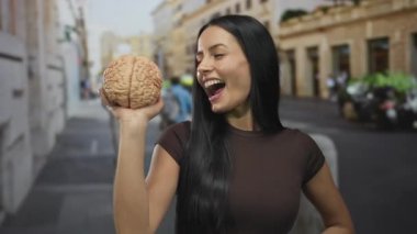 Kadın gülümseyen bir beyin modelini şehir sokaklarında günlük kıyafetlerle gezdirirken. Açık havada canlı bir yaşam tarzını ve zekasını simgeliyor..