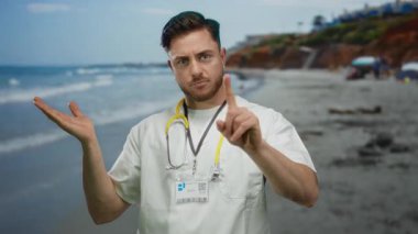 Steteskoplu genç sakallı bir adam güneşli bir sahil geçmişinde parmağı olmadan sakin bir deniz kenarında tıbbi otoritesini taşır..