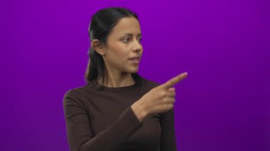 Canlı mor bir arka plan karşısında duran kadın, izole edilmiş bir stüdyo ortamında sürpriz ve merakı somutlaştırıyor..