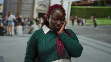 Pembe örgülü kadın İtalya 'daki sidik kulesinin önünde poz veriyor, turistlerle ve arka planda tarihi mimariyle huzurlu bir anı yakalıyor..