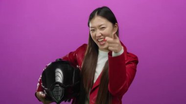 Kırmızı ceketli bir kadın canlı pembe arka plana karşı kaskını tutuyor modern tarz ve enerji gösterisi yapıyor.