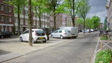 Amsterdam 'da park halindeki arabalar ve ağaçlar şehrin kendine özgü mimarisini yansıtan bokeh etkisi yaratıyor..