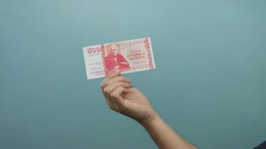 İzlanda 500 krona 'lık banknotu olan beyaz bir adam izole edilmiş bir mavi duvar arka planına karşı para ve finans unsurları sergiliyor..