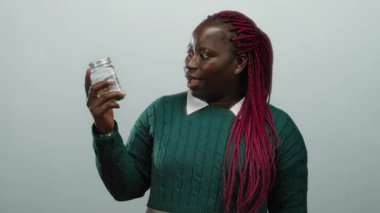 Beyaz arka plan üzerinde dolar banknotları olan bir kadın tasarruf kavramı sergiliyor ve sürpriz ve heyecan ifade ediyor.