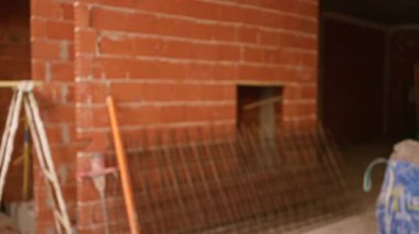 Tamamlanmamış tuğla duvarlar ve metal çubuklar içeren bir inşaat alanının bulanık arka planı