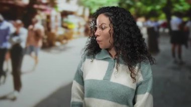 Dolu bir sokakta canlı bir geçmişi olan, gözlüklü ve süveterli bir kadın, canlı bir şehir ortamını öneriyor ve gençlik anı yakalıyor.