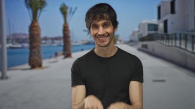 Siyah tişörtlü adam elleri ile kalp şekli yapar ve liman güvertesinde bir öpücük atar; romantik aşk.