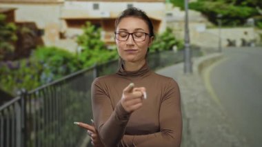 Güvenle ayakta duran ve parmakları şehir dışında bir sokak ortamını işaret eden dinamik bir şehir ortamında kendine güvenen ve odaklanan bir kadın..