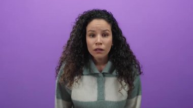 Mor bir arkaplan üzerinde duygularını ifade eden bir kadın, bir süveter giyiyor, yalıtılmış, gösterişli saç dokusu ve gençlik.