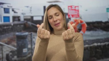 Genç sarışın kadın iskelede parmak kalp oluşturur; aşk, aşk, aşk, aşk, aşk, arkadaşlık..