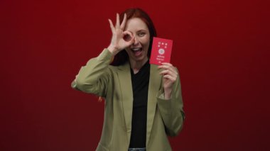 Japon pasaportlu bir kadın kırmızı arka planda poz veriyor, el hareketi yapıyor, kimlik teşhisi ve seyahat teması yapıyor..