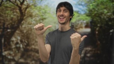 Gri gömlekli adam gündüz vakti güneşli yeşil orman yolunda göğsünü işaret ediyor. Kendine güven..