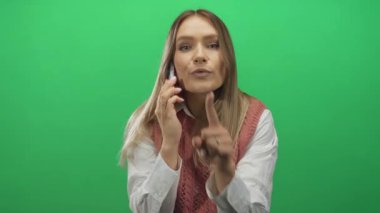 Yeşil izole edilmiş arka planda telefonla konuşan, rahat kıyafetler giyen ve canlı bir ortamda duygularını ifade eden bir kadın.