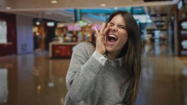 İçerideki alışveriş merkezinin arka planında gülen bir kadın neşe ve enerji taşıyor..