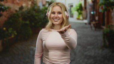 Kulaklıklı genç bir kadın şehir caddesinde, şehir içinde rahat ve modern bir atmosferi somutlaştırıyor..