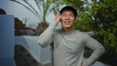 Parkta genç bir adam, doğal yeşil bir geçmişe karşı bir fikri varmış gibi güler ve bir ilham ve mutluluk anı yakalar..