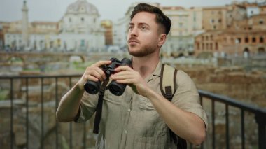 Dürbünlü ve sırt çantalı genç adam Roma harabelerini keşfediyor, tarihi bir mekanda bir turist macerasının özünü yakalıyor..