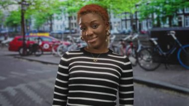 Yüzü sokakta görünen, kızıl saçlı, çizgili bluzlu, altın kolyeli ve halka küpeli bir kadın..