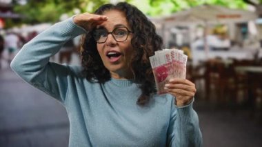 Şehrin dışındaki kadınlar ellerinde İzlanda banknotları tutarken, gözlük takarken, neşeli bir ifadeyle mavi bir kazak giyerken, finansal başarı ve heyecan öneriyor..