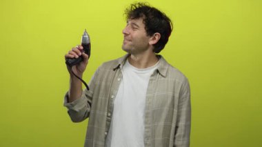 İspanyol adam elinde tornavidayla gülümserken parlak sarı bir arkaplan tutuyor..