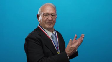 Takım elbiseli kıdemli bir adam, parlak mavi bir arkaplan karşısında özgüvenle gülümseyen bir şirket ortamında başarı ve profesyonellik sergiliyor..