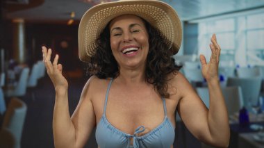 Hasır şapkalı İspanyol kadın, rahat bir atmosferi olan bir restoranda gülümsüyor, zarafeti ve evde rahatlığı harmanlıyor..