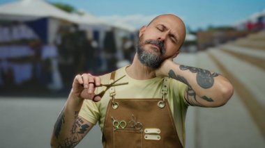 Sakallı ve makaslı dövmeli adam şehir sokaklarında yorgun görünüyor, engebeli cazibe ve açık havada sanatsal yetenekleri var..