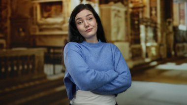 Katolik kilisesinde kendine güvenen bir kadın, esmer saçlı, mavi kazaklı, dinsel mimari ortamına ışıldayan bir güzellik ve zarafet katıyor..