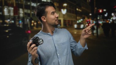 Gecenin bir vakti elinde kamera tutan İspanyol genç adam dışarıda beliren bulanık ışıklarla şehir caddesinde gülümsüyor..